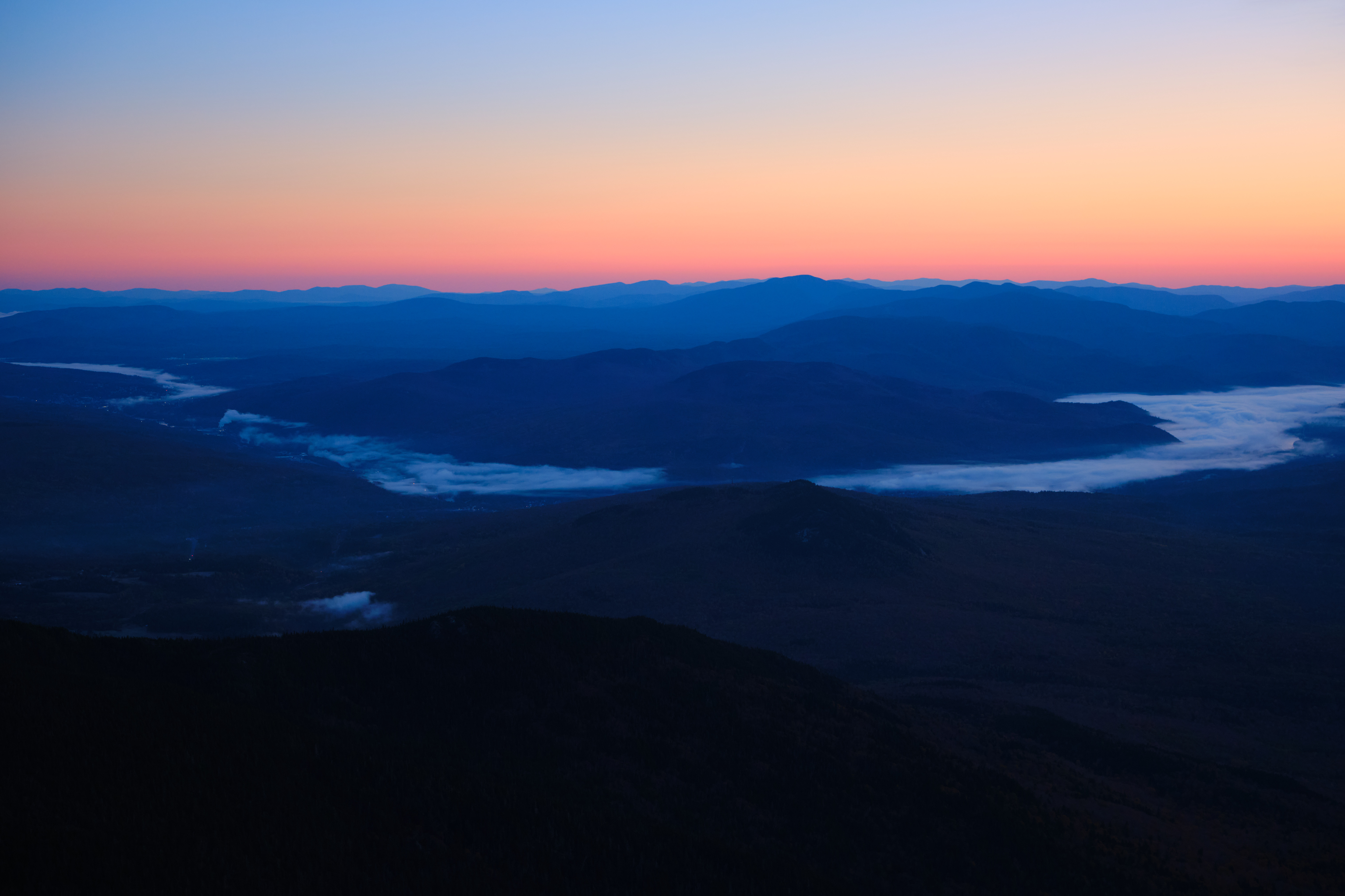 Bright red sunrise over a mountain range behind a deep blue sky.